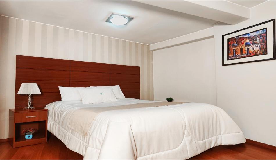 a bedroom with a large bed with a wooden headboard at HOTEL MURCIA AREQUIPA in Arequipa