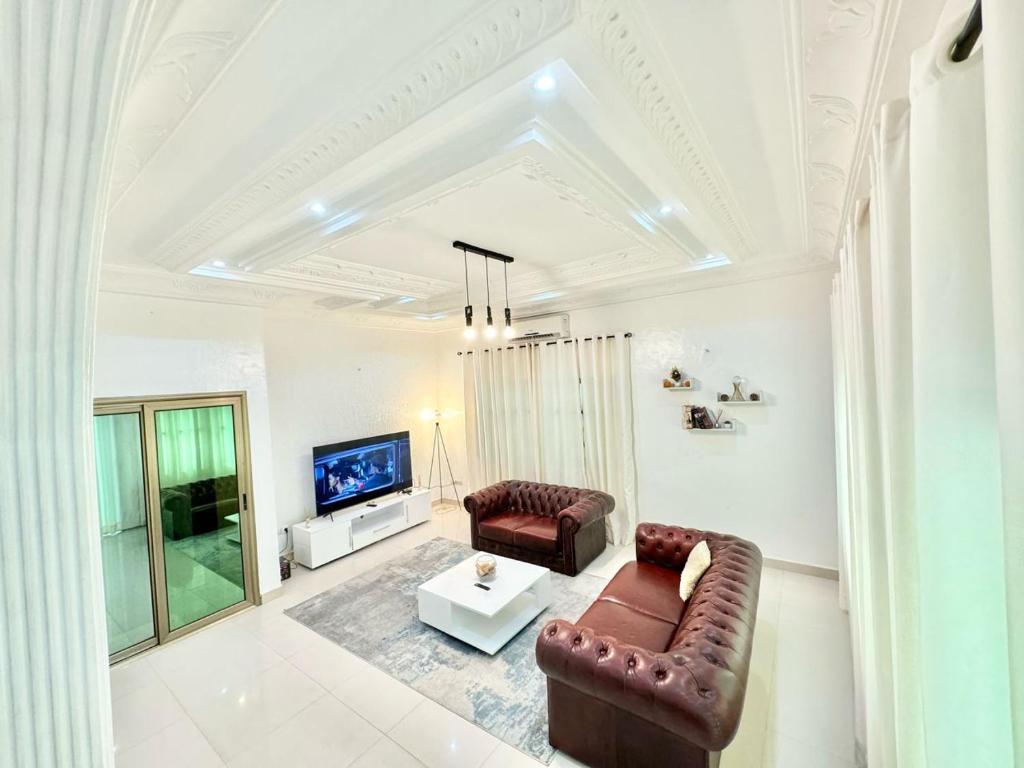 a living room with a couch and a tv at Résidence La Rose des Vents in Cotonou