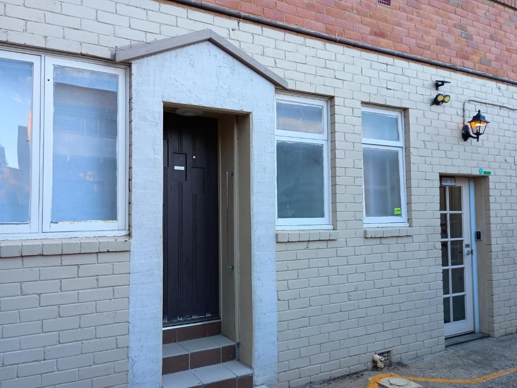 a white brick building with a black door and windows at Cooma Center Cortina Studio in Cooma