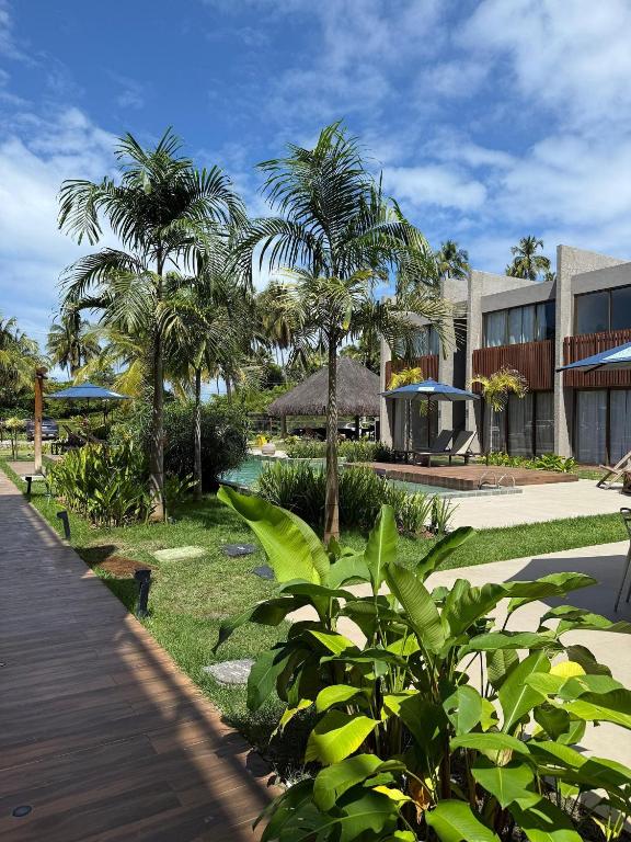a resort with palm trees and a wooden walkway at Beira Mar Japaratinga Brisa in Japaratinga
