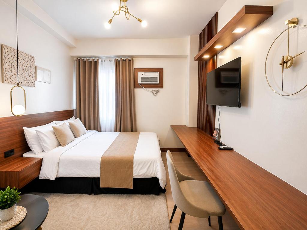 a hotel room with a bed and a desk at The Narci Suites in Manila