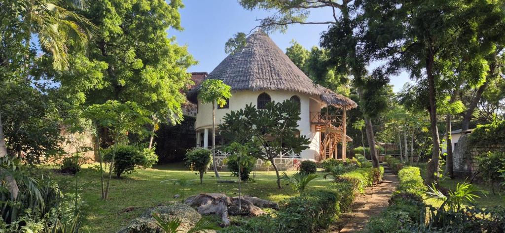 a house with a thatched roof in a garden at The Mousa House in Malindi