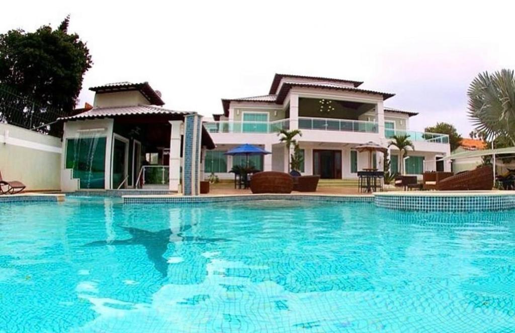 a large swimming pool in front of a house at Mansão Bolsoni in Saquarema