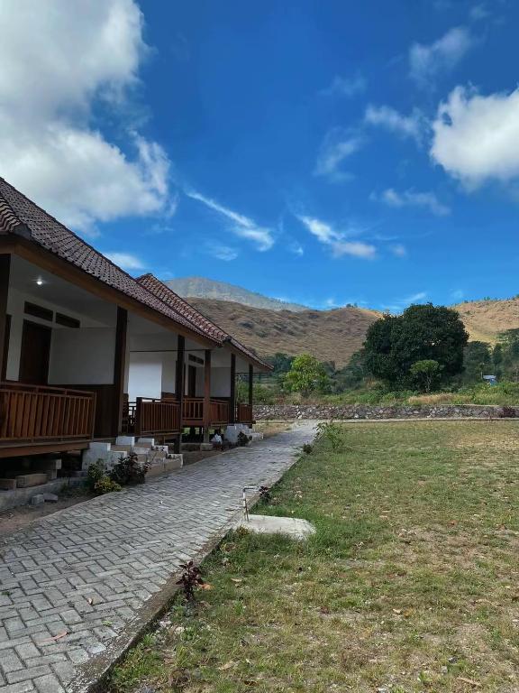 a house with a brick walkway next to a field at Katra Sembalun in Sembalun Lawang