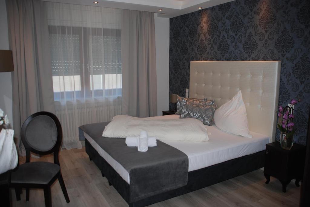 een slaapkamer met een bed, een stoel en een raam bij Hotel zur Linde in Hanau am Main