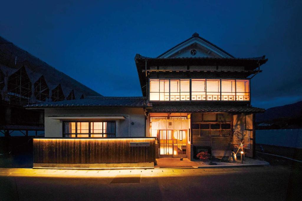 a house with a lit up facade at night at あかり by 4S STAY in Uchiko