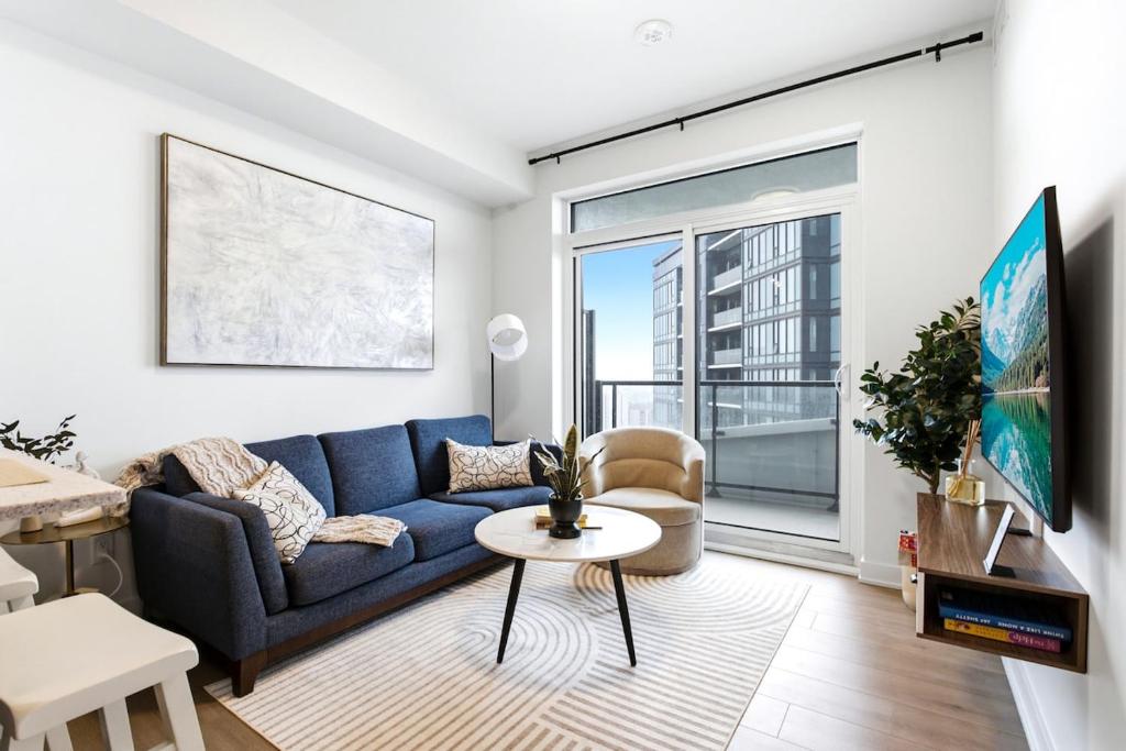 a living room with a blue couch and a large window at Stylish Skyview Condo in Kitchener Downtown in Kitchener