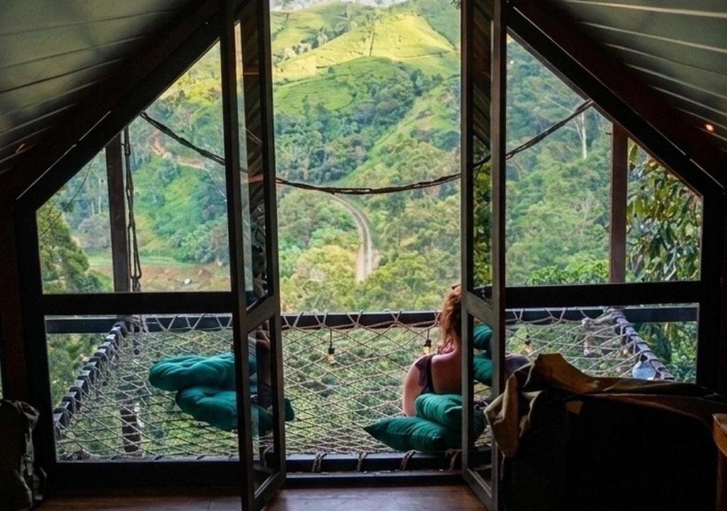a woman sitting in a room with a view from a window at Fern Hill Cabins in Ella