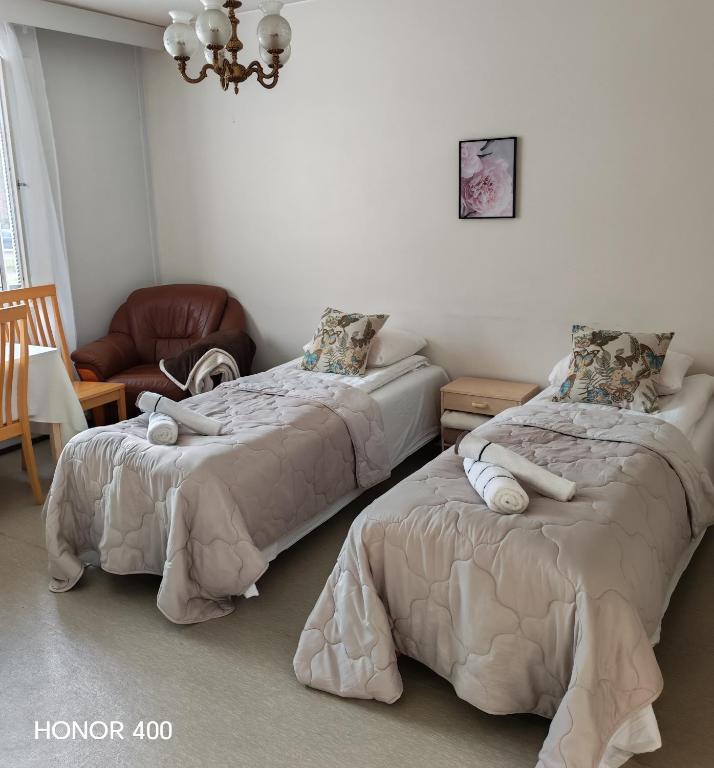 a bedroom with two beds and a chair at Light Home in Sodankylä