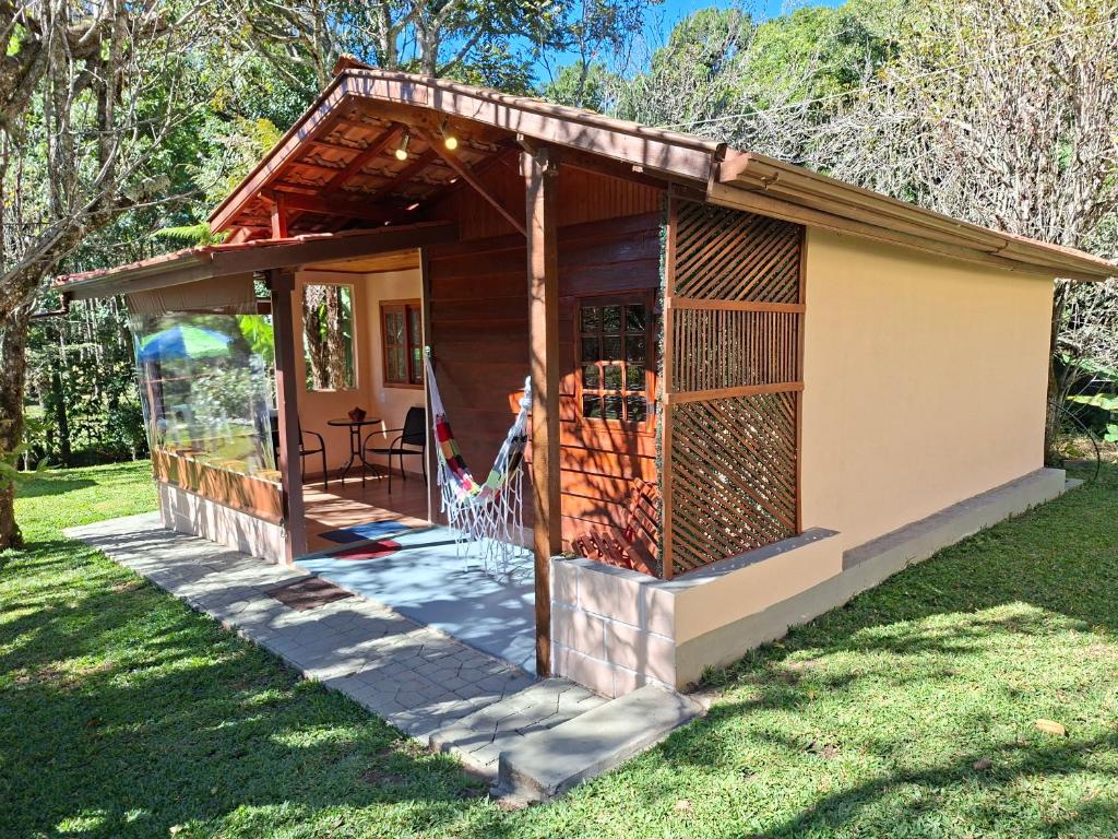 ein winziges Haus mit Veranda im Gras in der Unterkunft Chalé Cabana Ruby in Gonçalves