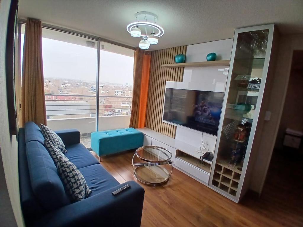 a living room with a blue couch and a large window at Departamento VIP estreno en Condominio in Lima