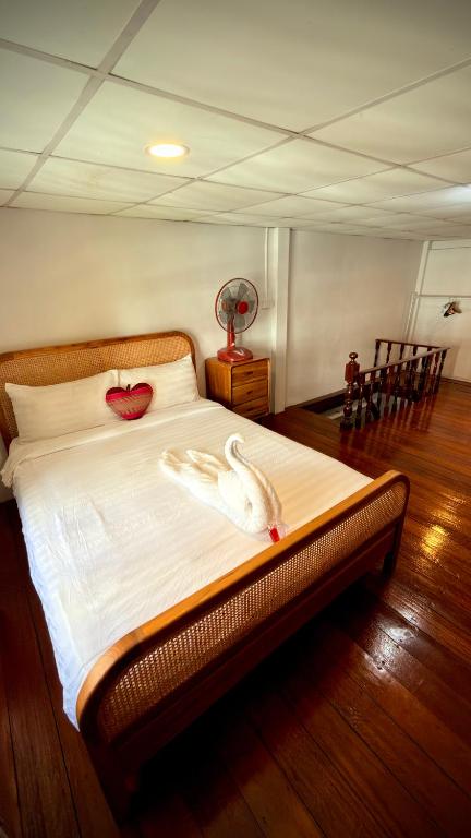 a bedroom with a bed with a swan on it at Traditional Thai House Chaloklum in Chaloklum