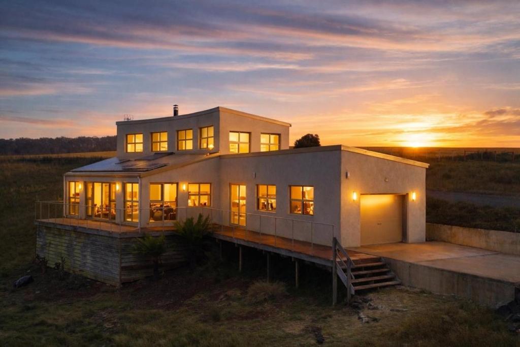 a large house with the sun setting behind it at The Hemp House | Table Cape Ocean Views in Table Cape