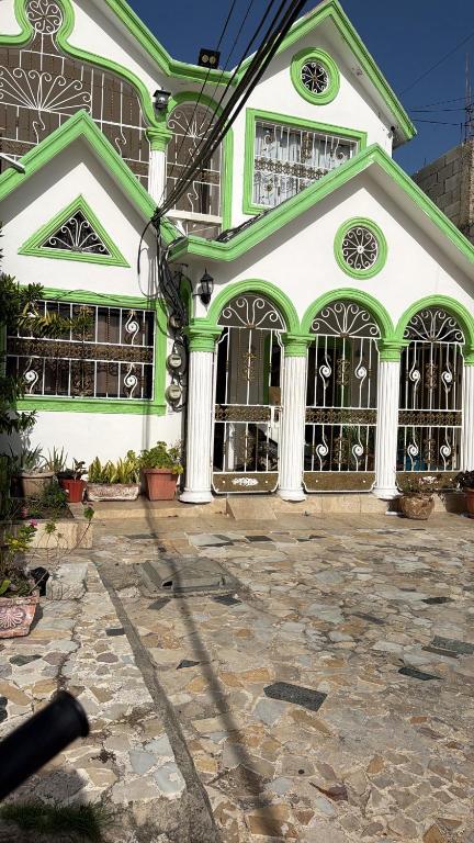 a large green and white building with gates at Samana house in Santa Bárbara de Samaná