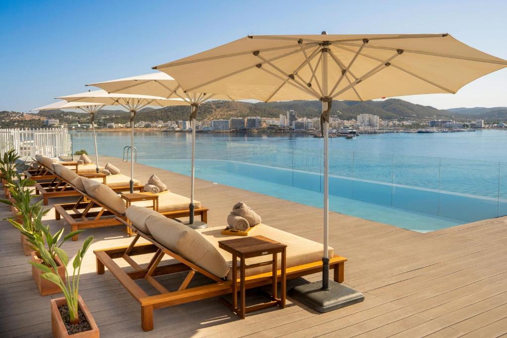 a row of chairs and umbrellas next to a pool at INNSiDE by Meliá Ibiza Beach in San Antonio Bay