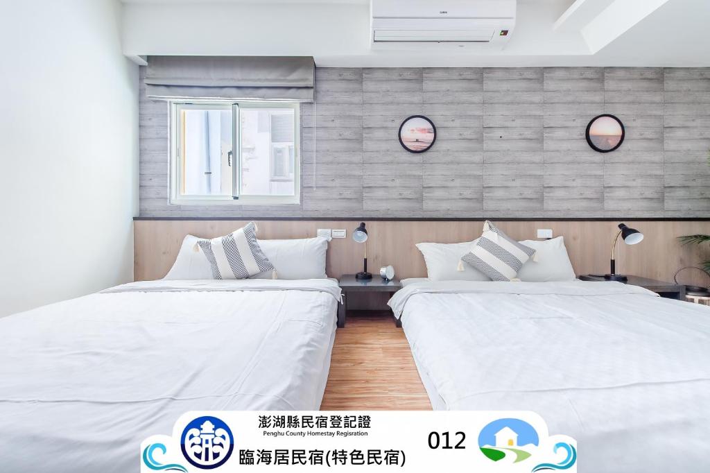 two beds in a room with white sheets at Penghu Sea Residences Hall in Magong