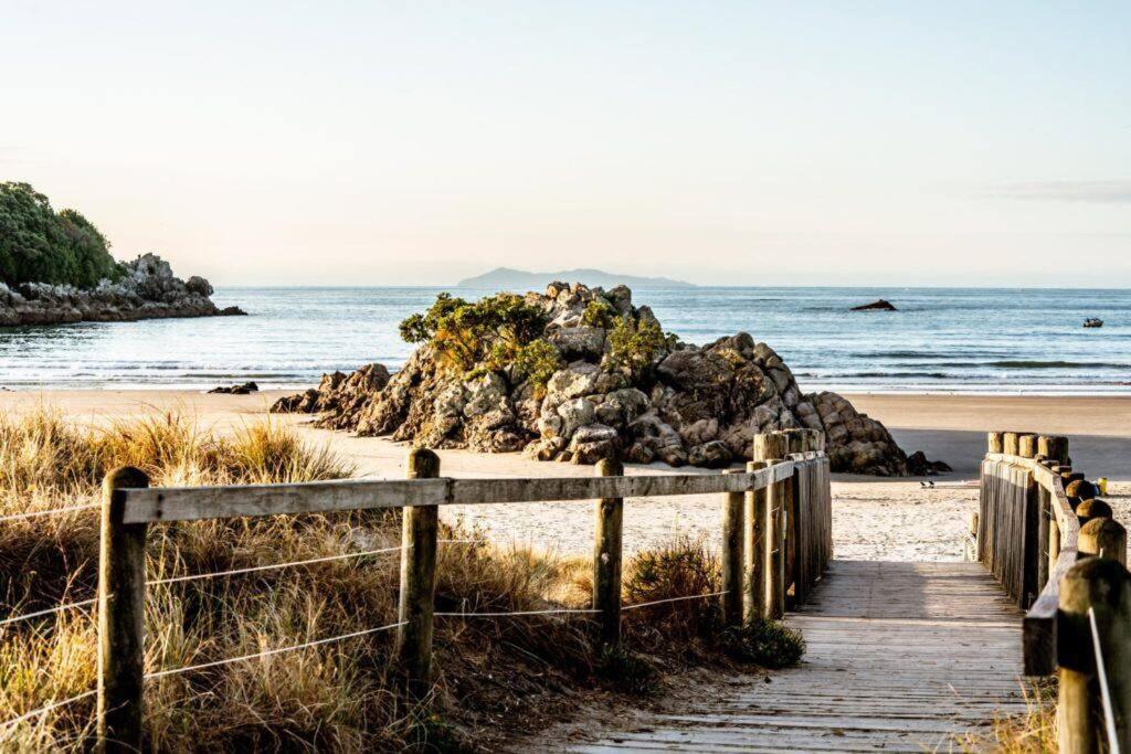 a wooden path leading to a beach with rocks at Beachfront Marine Parade in Mount Maunganui