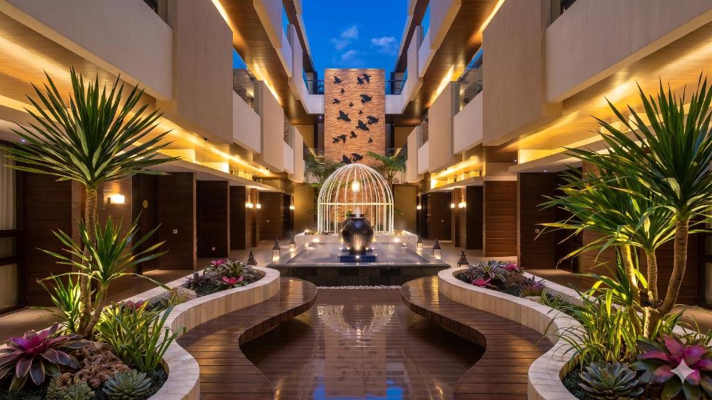 a hotel lobby with a fountain and palm trees at Sweet Garden Guest House in Malang