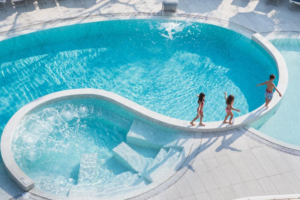 eine Gruppe von Menschen, die um einen Pool spazieren in der Unterkunft Blu Suite Resort in Bellaria-Igea Marina