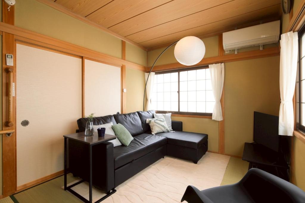 a living room with a black couch and a window at Matsumoto BASE in Matsumoto