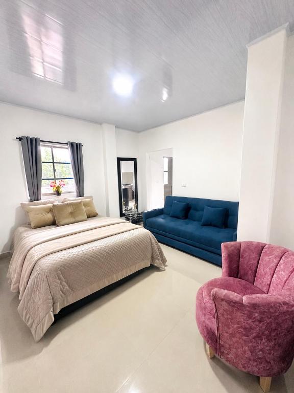 a bedroom with a bed and a couch and a chair at Sol caribe aptos in Santiago