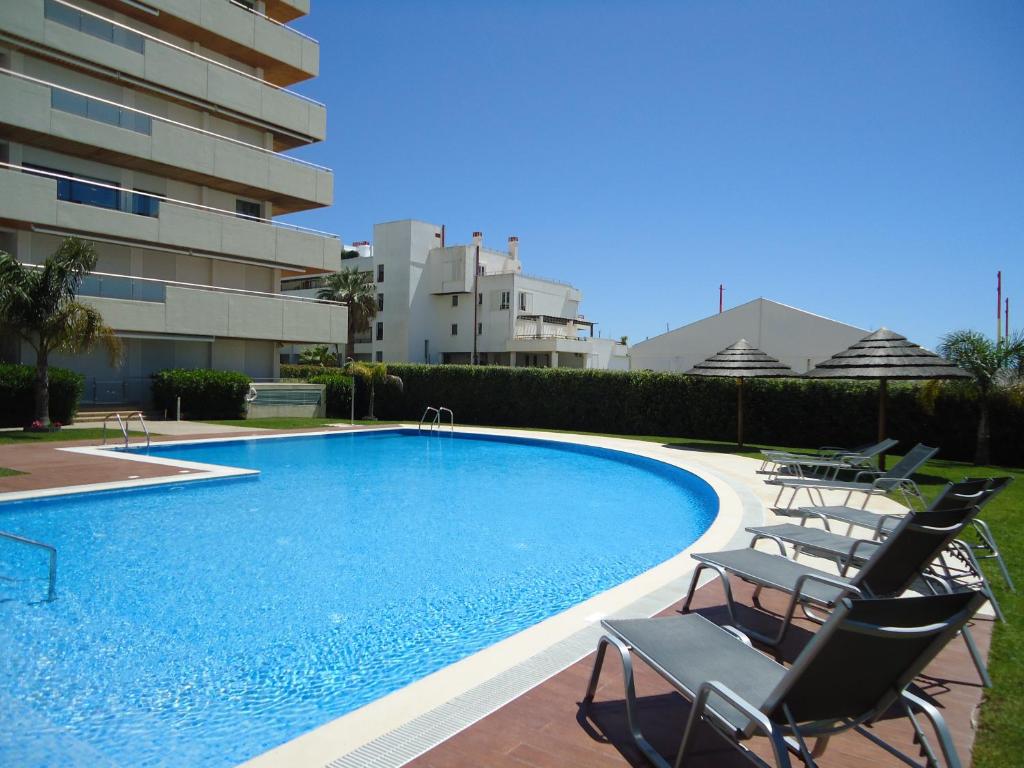 una piscina con sillas junto a un edificio en Marina Vilamoura Apartment, en Vilamoura