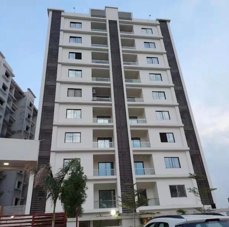 a tall white apartment building with cars parked in front of it at cloud nine in Boria Kalān