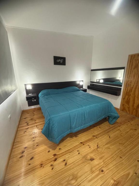 a bedroom with a blue bed and a wooden floor at Acordes de Gaitas - Departamento 3 in Malargüe