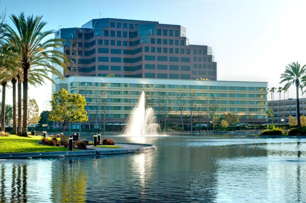 a fountain in a lake in front of a building at voco Orange County - Airport by IHG in Santa Ana