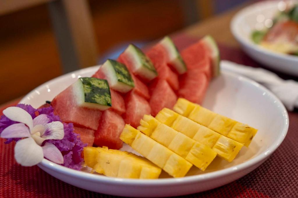 A fruit plate with watermelon and pineapple, decorated with an orchid.