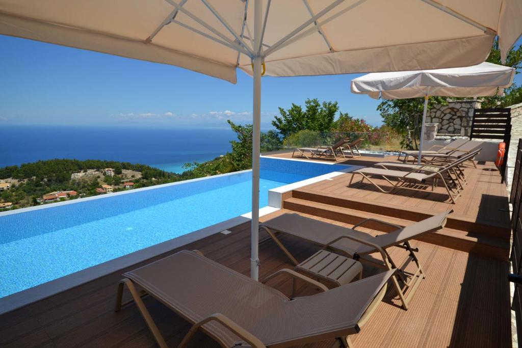 a view of a swimming pool with chairs and an umbrella at Lefkada Sunset Villa in Kalamitsi