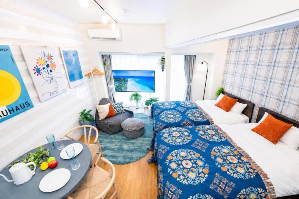 a room with two beds and a table in it at 旅鴉 inn 高松 - 高松駅徒歩5分 in Takamatsu
