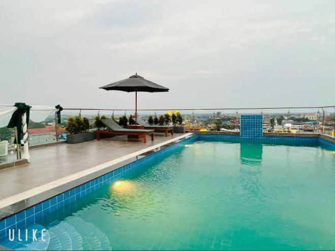 a large swimming pool with an umbrella on a building at Khemra Kampot Hotel in Kampot in Kampot