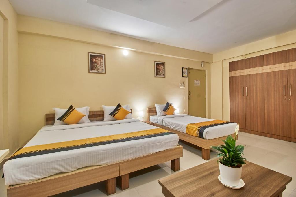 a bedroom with two beds and a table at Itsy Hotels Emirates Suites - Near RMZ EcoWorld, Bellandur in Bangalore