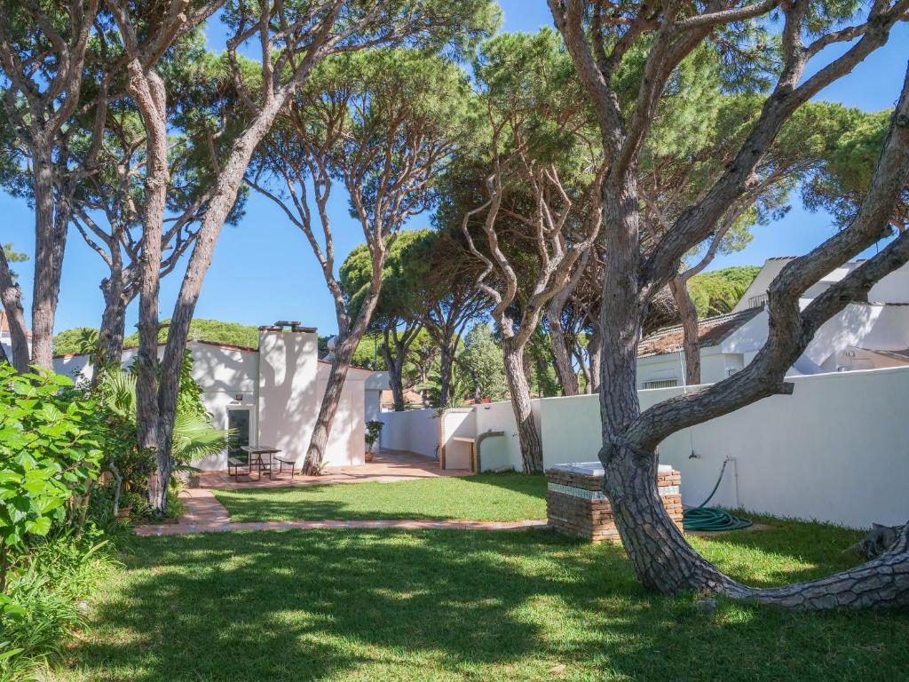 a yard with trees and a white fence at Chalet La Caballa Playa la Barrosa in Chiclana de la Frontera