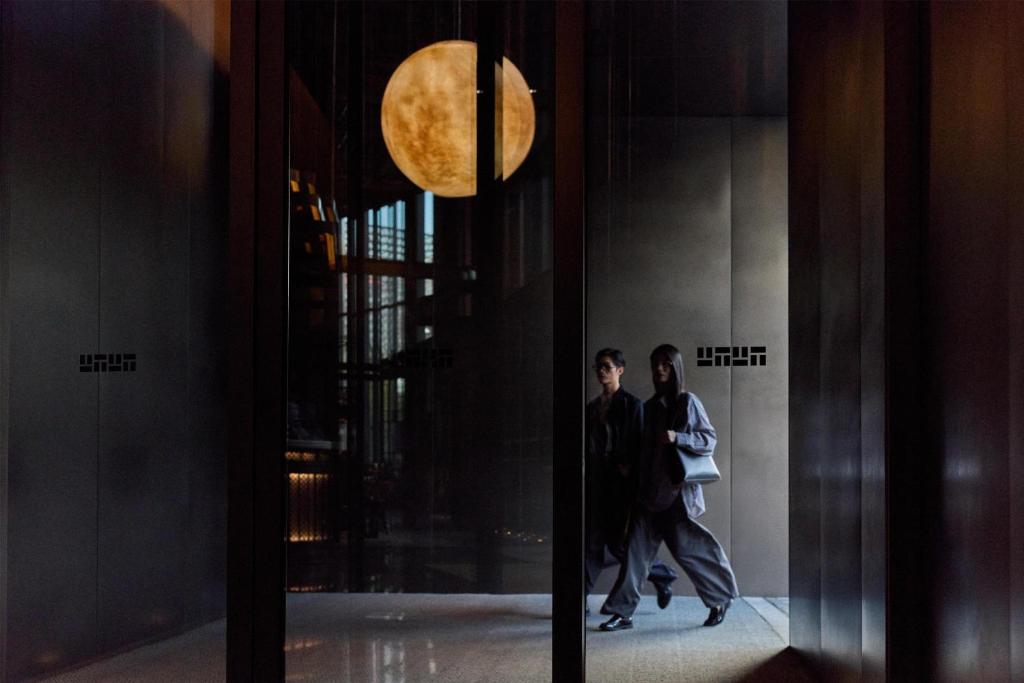 two people walking down a hallway in a building at Thompson Shanghai Expo, by Hyatt in Shanghai