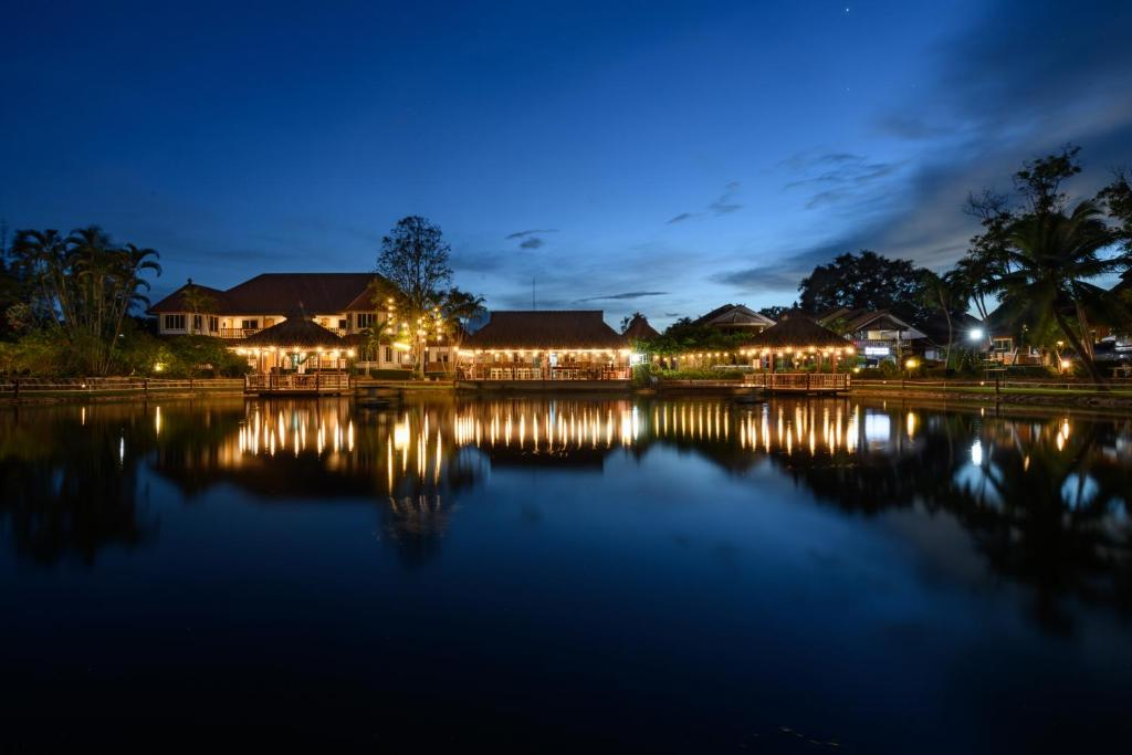 a villa at night with lights on the water at Reaunnapa Resort in Ban Nong Kham