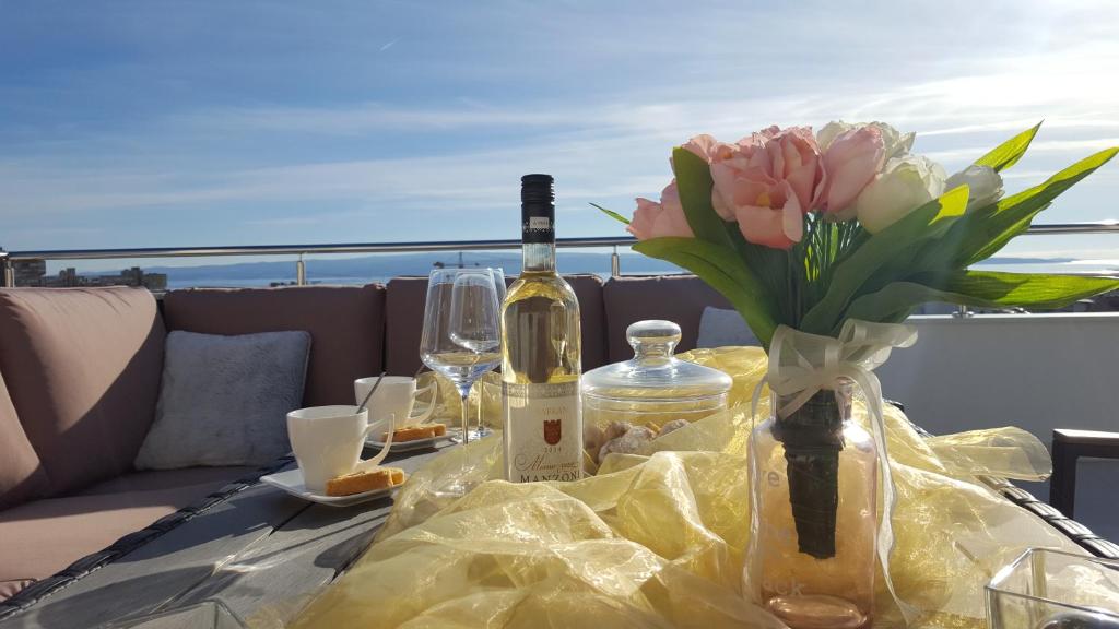 uma mesa com uma garrafa de vinho e um vaso de flores em Three Roses em Split