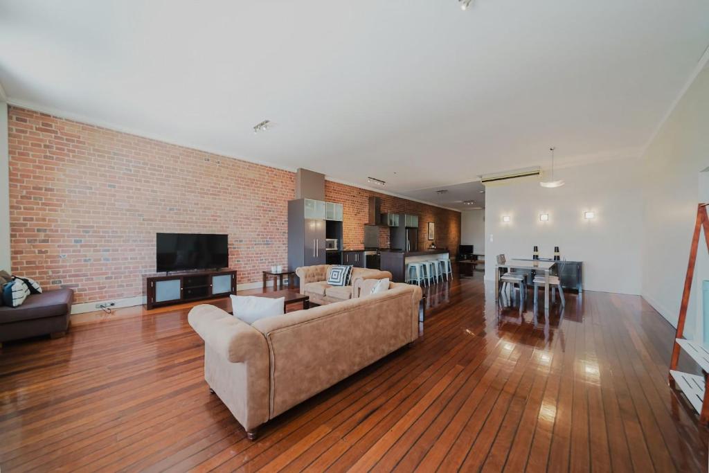 a living room with two couches and a brick wall at Flinders 2 bed apartment near the Strand in Townsville