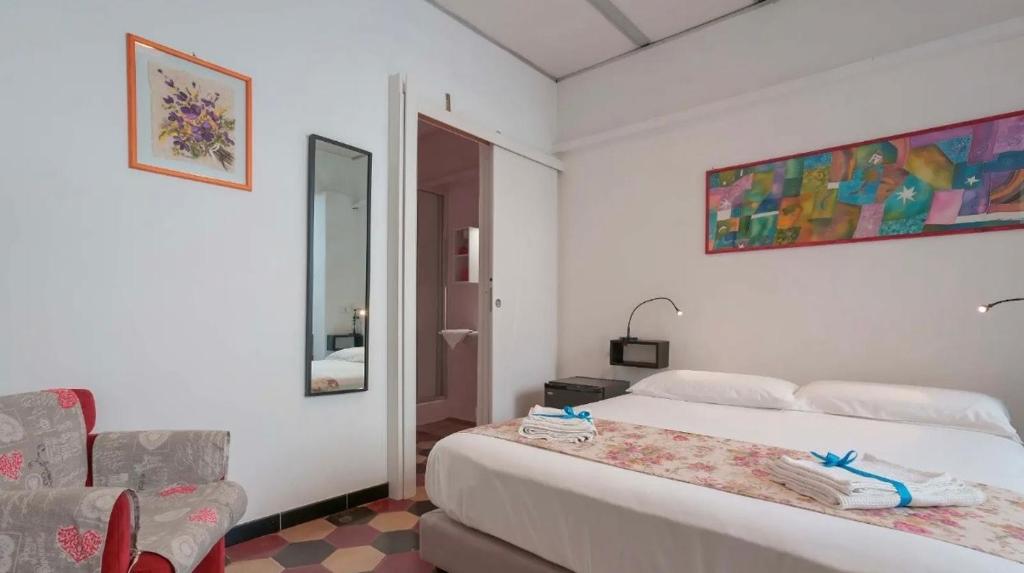 a white bedroom with a bed and a chair at Lungomare Casa Diaz in Cagliari