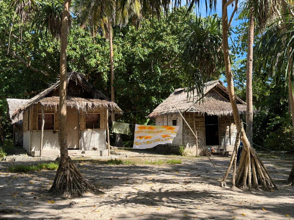 a small house with a straw roof and two palm trees at Twin Beach Bungalows in Loh