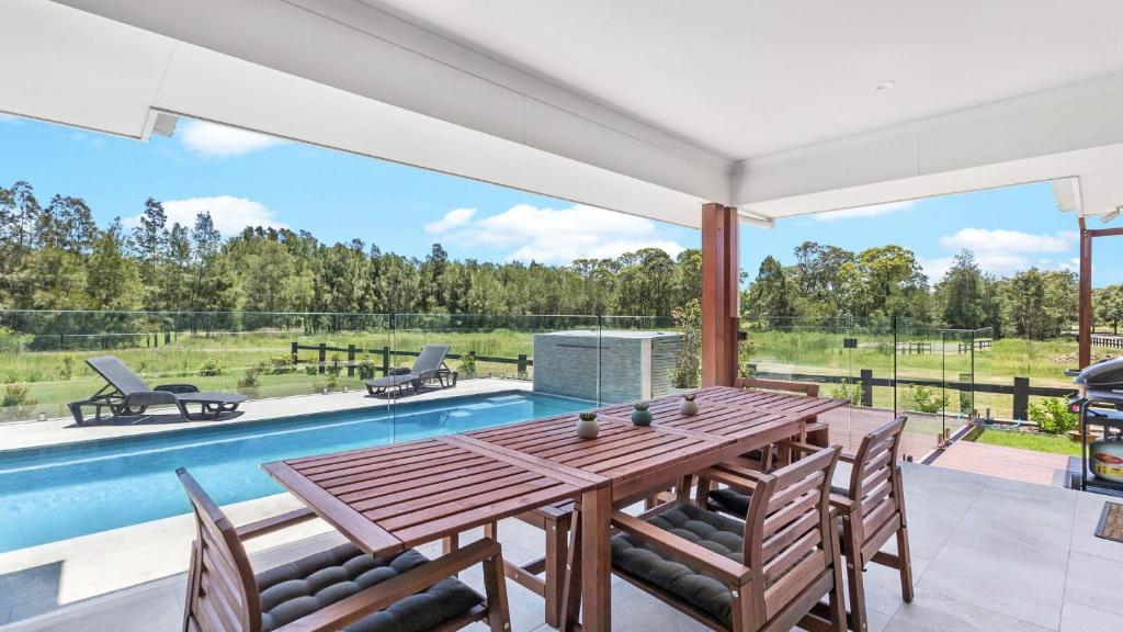 a dining room with a table and chairs and a pool at Kokoon in Pokolbin