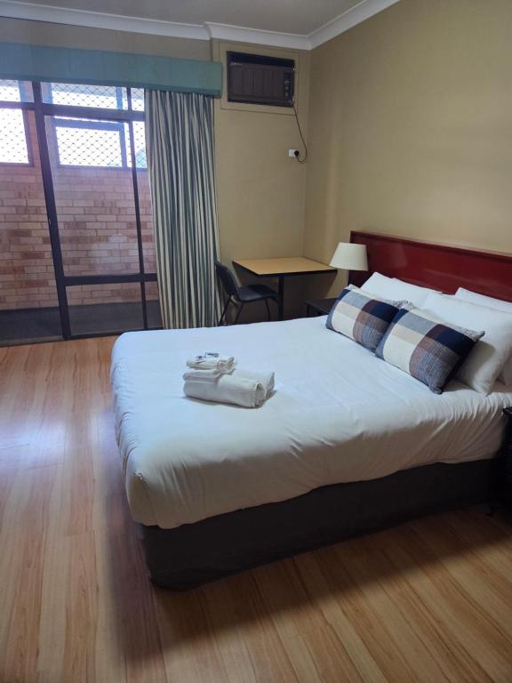 a hotel room with a bed with towels on it at Ashmont Inn Hotel in Wagga Wagga