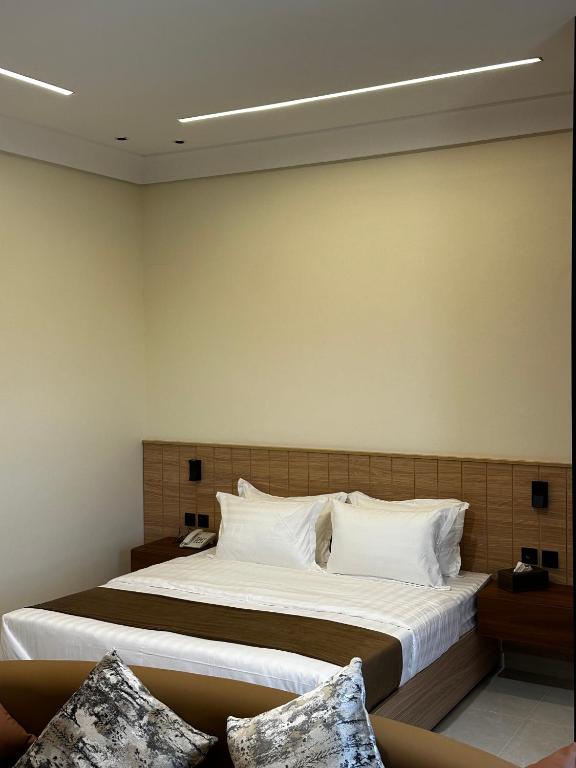 a bedroom with a large bed with white pillows at بيوت عطلات البيت الريفي للضيافه السياحي in Al Namas