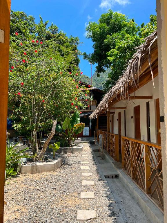 a courtyard of a house with trees and red flowers at Pugad Hostel, El Nido in El Nido