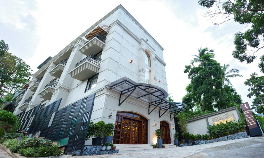 a large white building with a large door at Raphilhin The Business Hotel in Perintalmanna