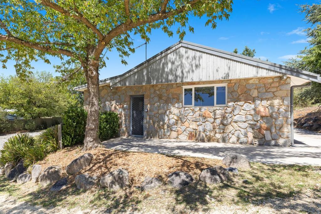 a stone house with a tree in front of it at Rock On Studio in Jindabyne