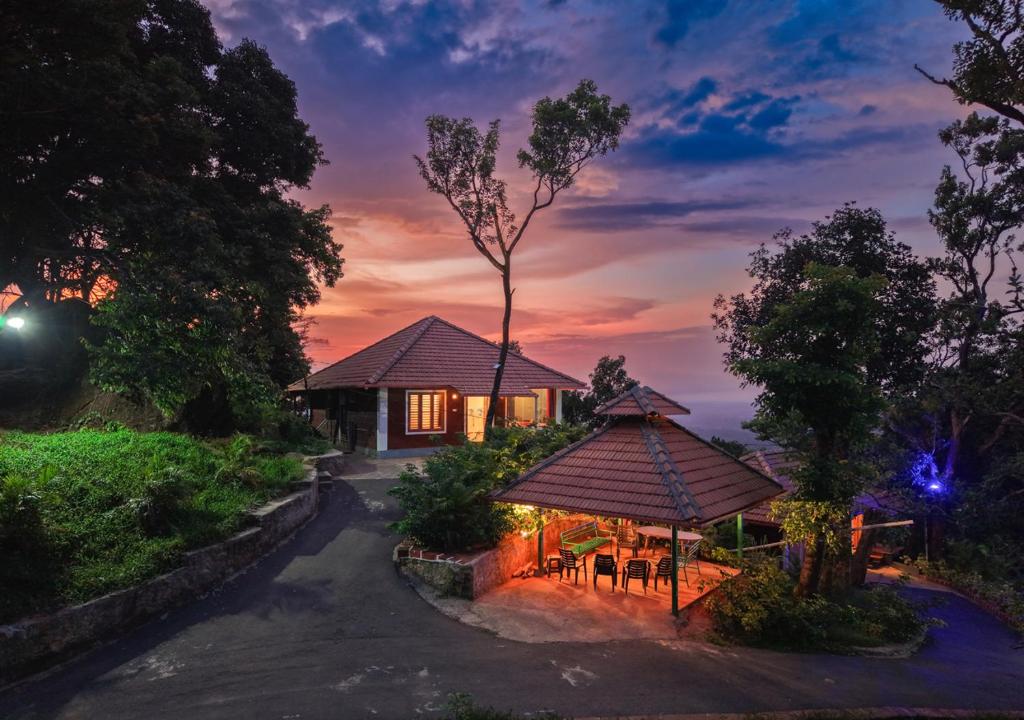 a house with a gazebo in front of a sunset at Celestial Heights Coorg by VOYE HOMES with Sunset views-Near to Nagarhole Tiger Reserve in Srimangala