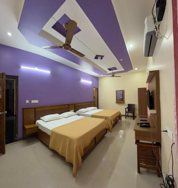 two beds in a room with a purple ceiling at Gravity Groups Core - Sakthi residency in Puducherry Airpoert