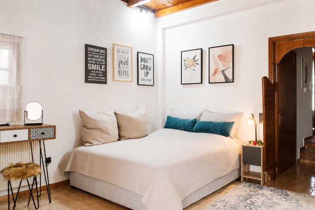 a bedroom with a white bed and some pictures on the wall at Stathohouse - Peaceful Balcony Retreat in Filiatra in Filiatra